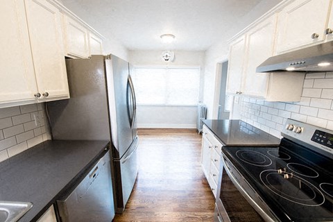 A kitchen with a black stove top oven and a black counter top.