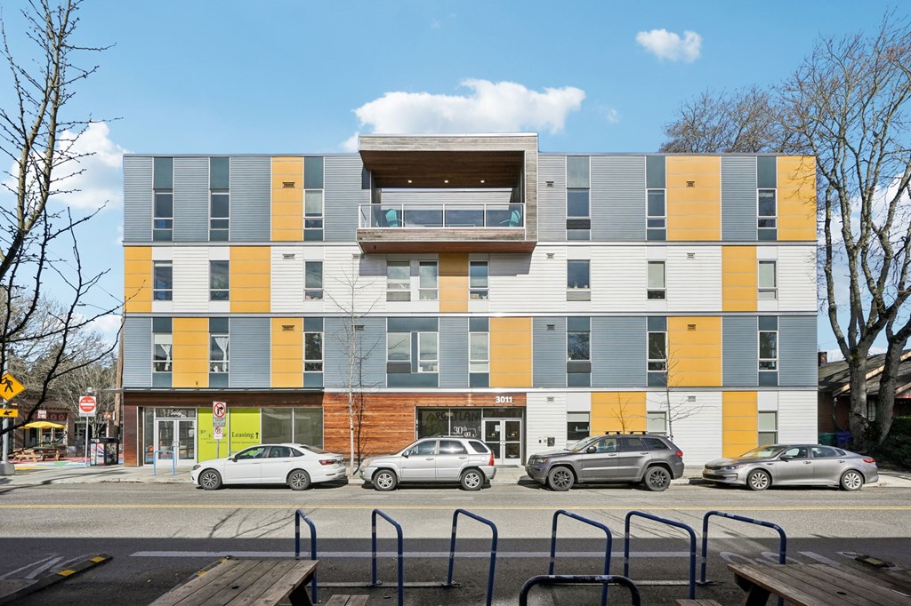 A modern multi-story building with a balcony on the top floor.