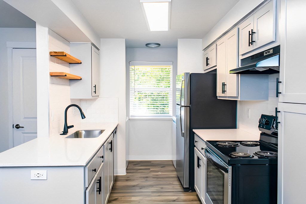 A kitchen with white cabinets and black appliances.