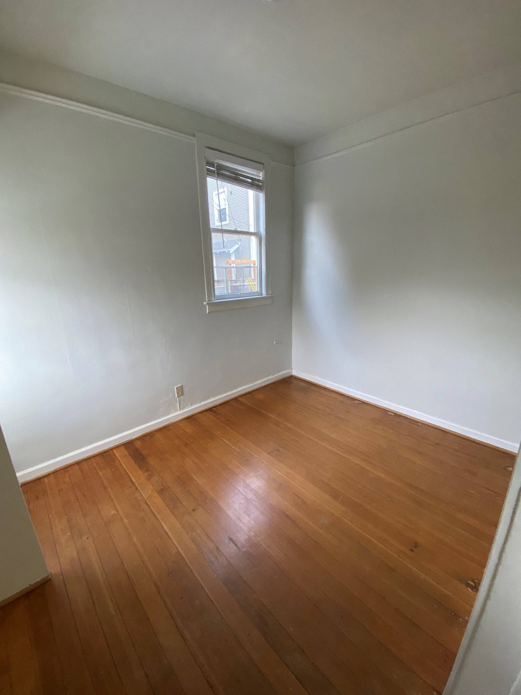 an empty room with wood floors and a window