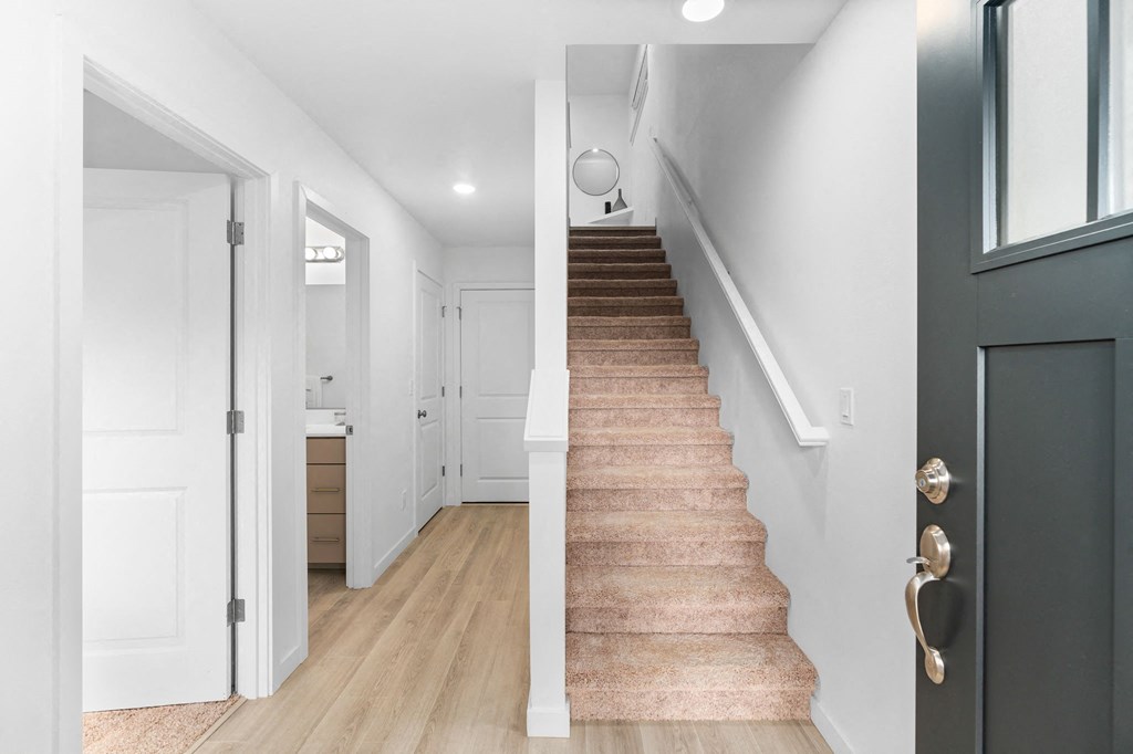a staircase in a home with white walls and wood floors