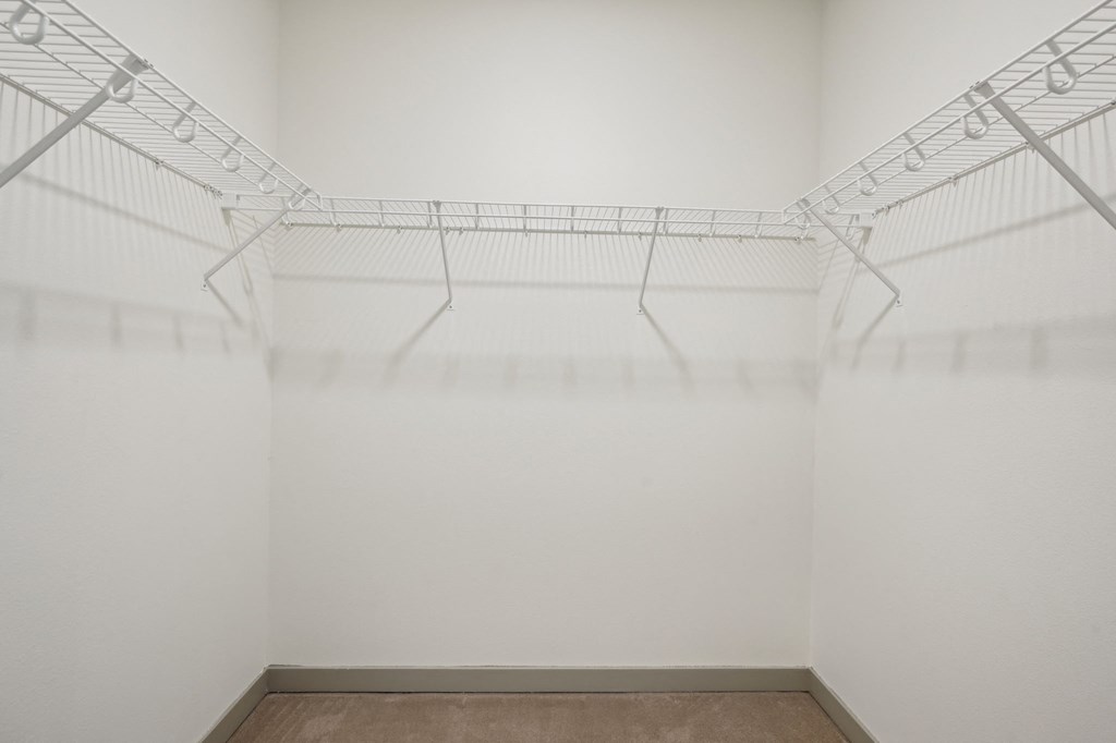A white wire shelf in a white room with a brown floor.