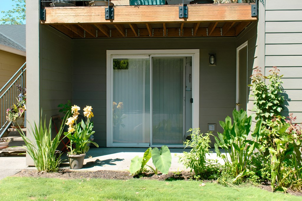 A white door with a glass panel is on a house with a wooden porch.
