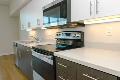 A modern kitchen with a black stove top oven and white countertops.