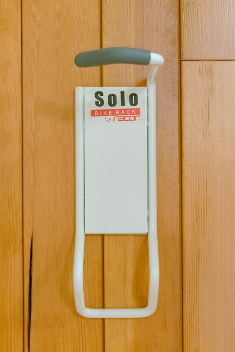 A white bike rack with a black handle and a red and black sign that says