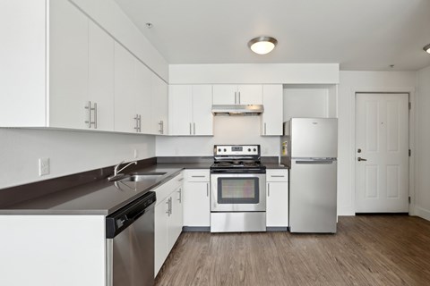 A modern kitchen with white cabinets and stainless steel appliances.