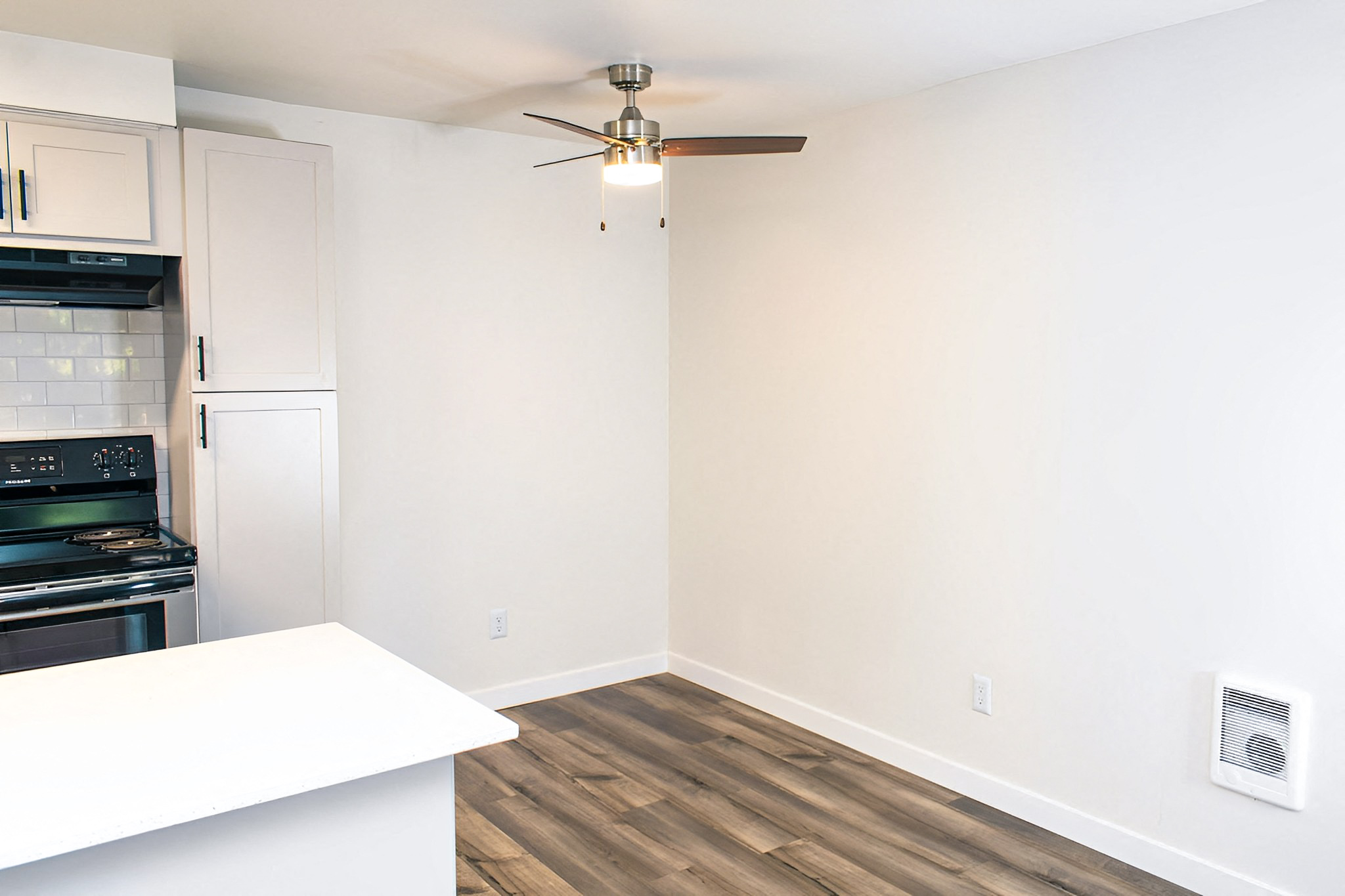 A kitchen with a stove top oven and a fan on the ceiling.