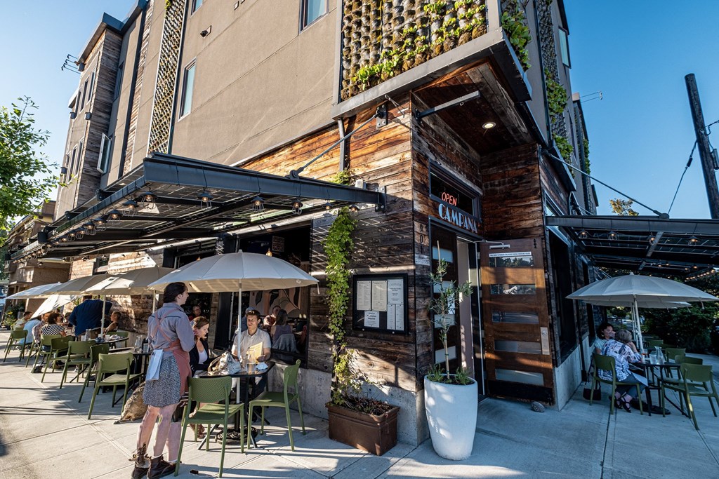 people sitting at tables outside of a restaurant