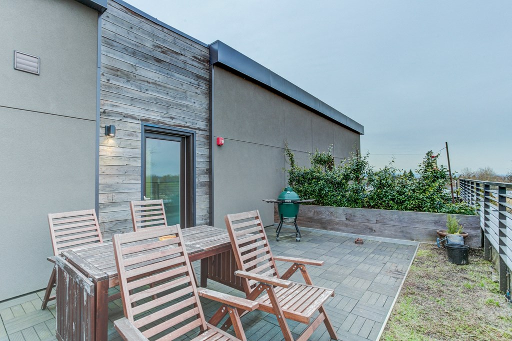 a patio with wooden chairs and a table outside of a house