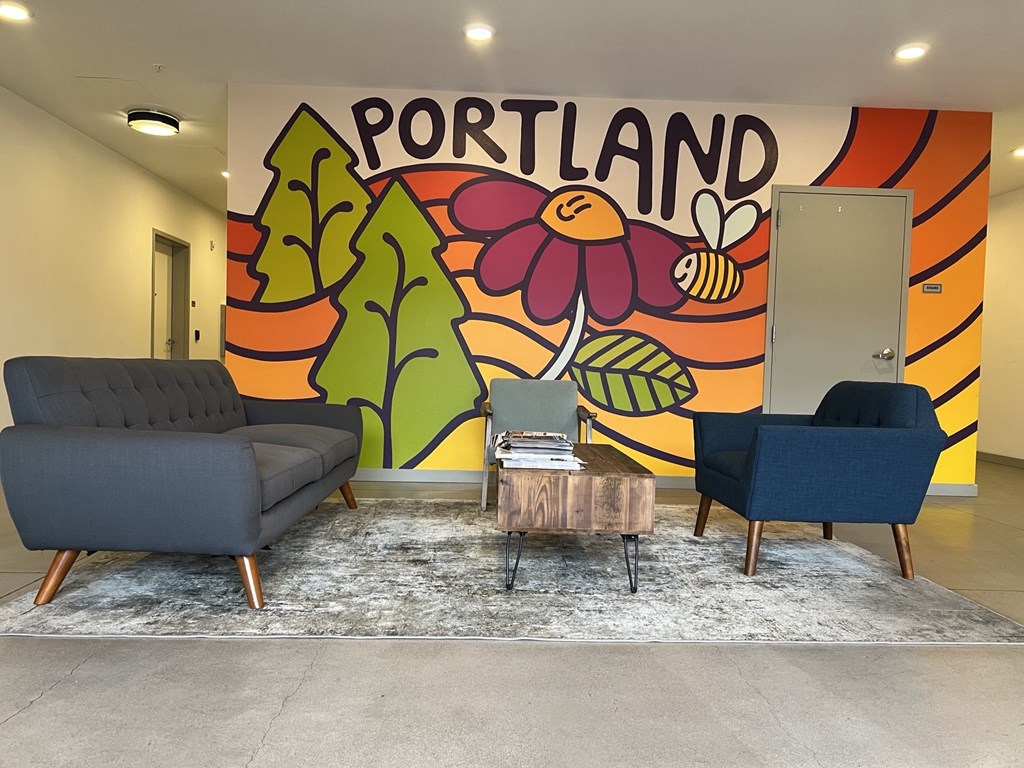 A room with a Portland mural on the wall and two chairs and a table in front of it.