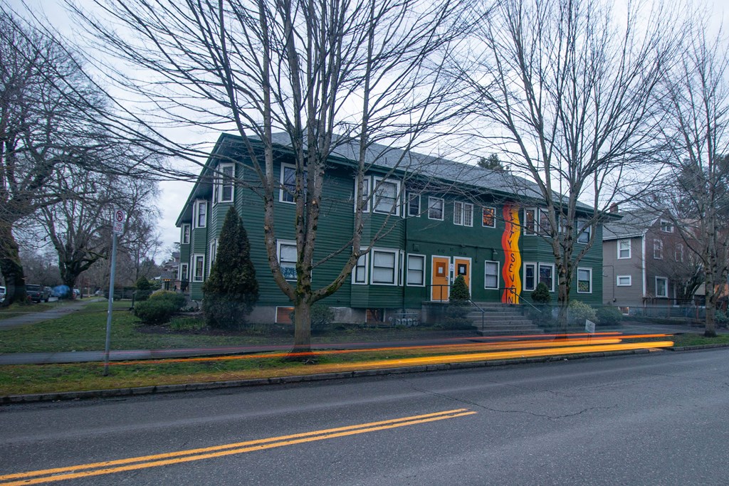 a green house with a flag on the side of a street