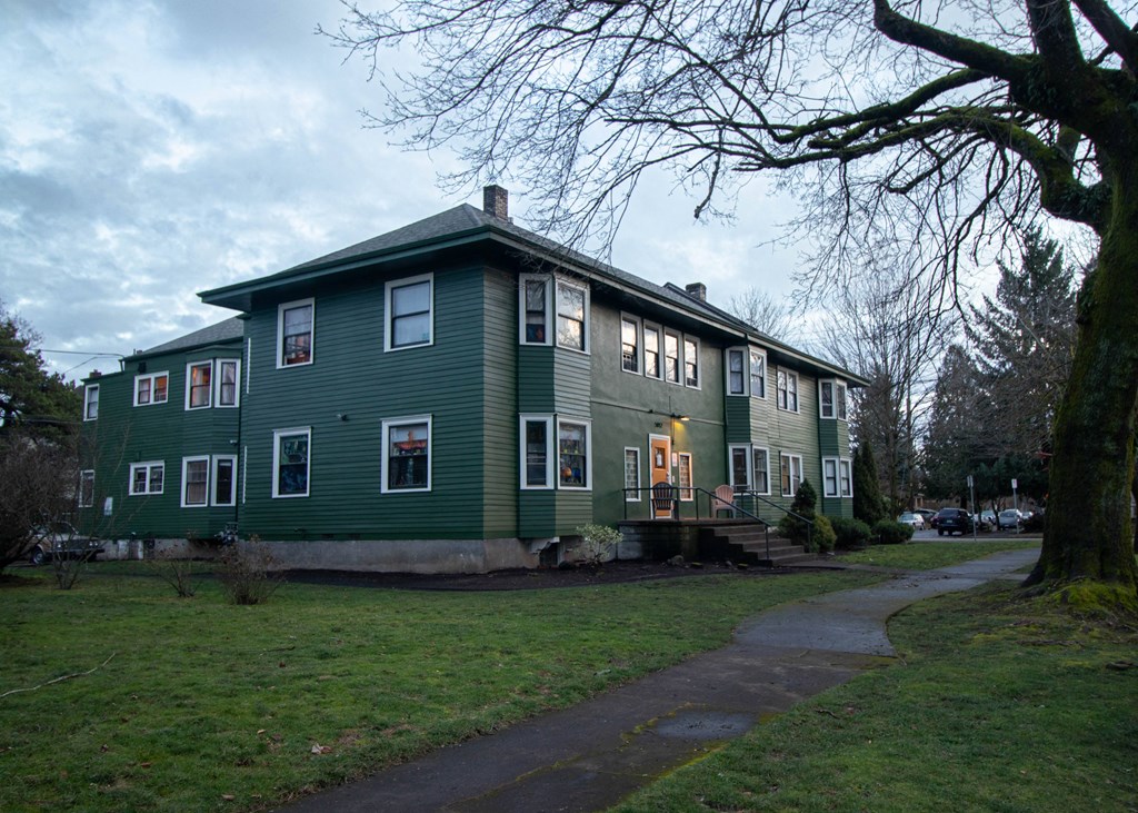 a green house with a sidewalk in front of it