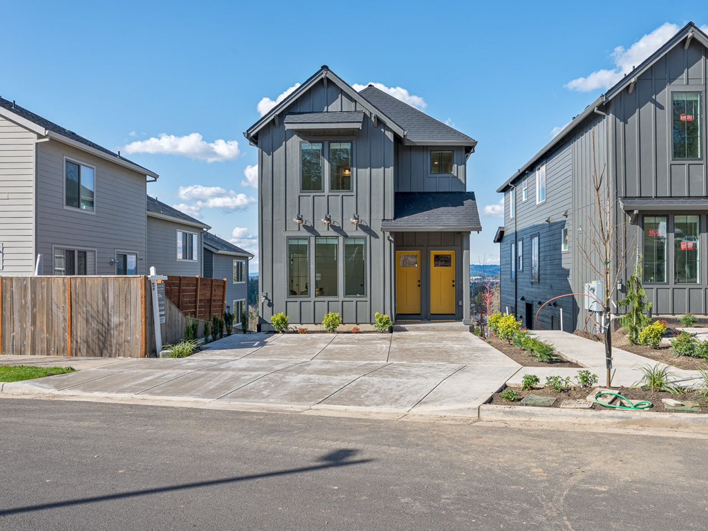 A modern house with a yellow door is surrounded by other houses.