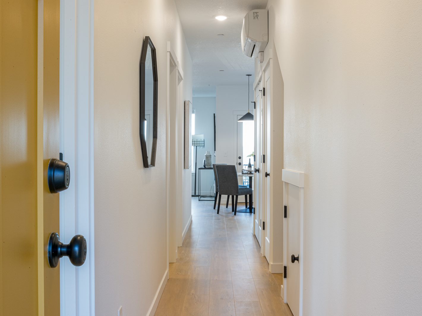 A hallway with a black door and a mirror on the wall.