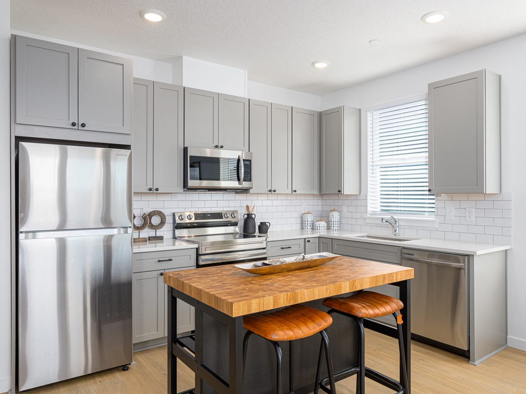 A modern kitchen with a wooden island and stainless steel appliances.