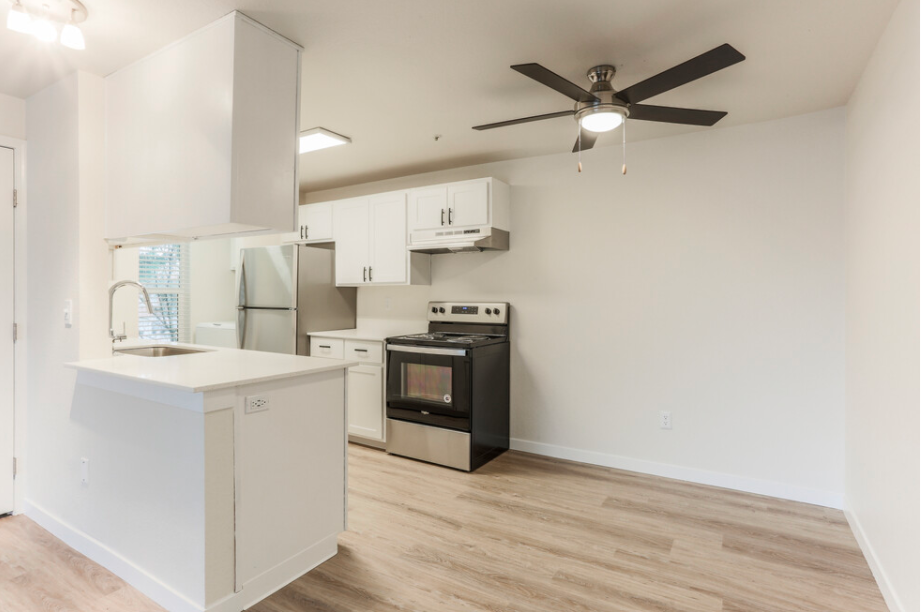 A kitchen with a black oven and white cabinets.