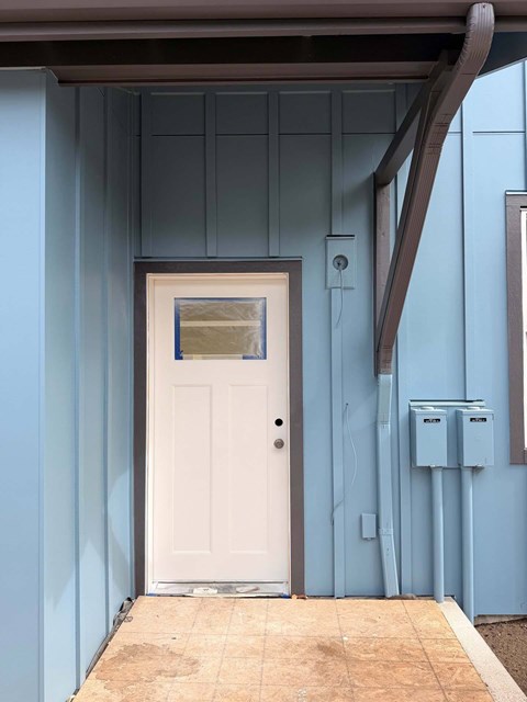A white door is closed and has a small window above it.