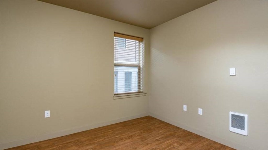 an empty room with a window and a wooden floor