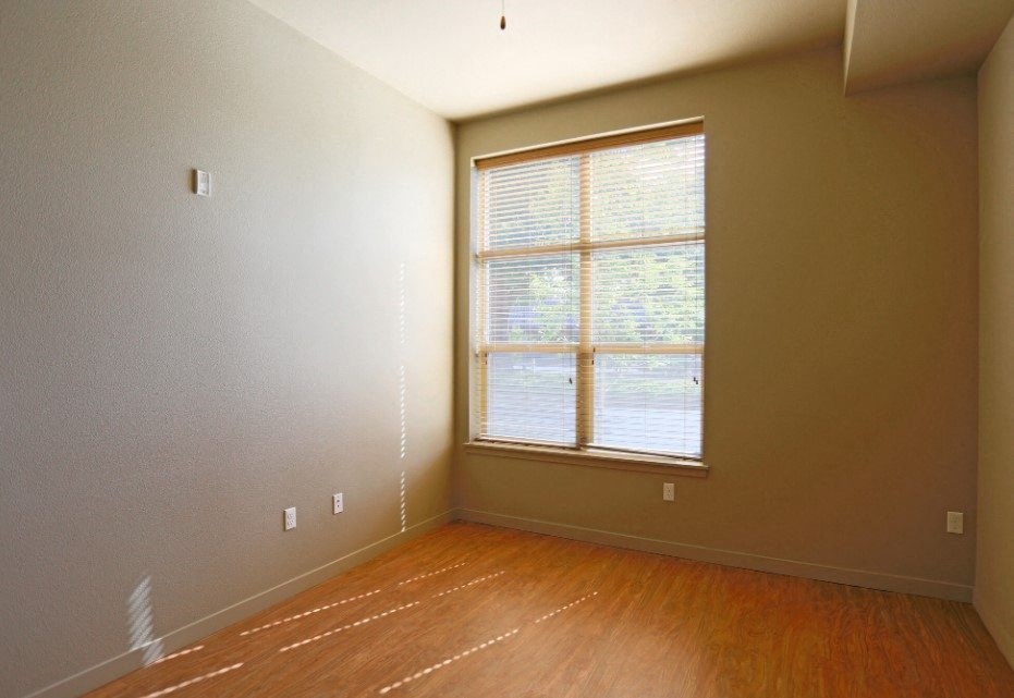 a bedroom with a large window and wooden floors