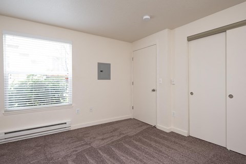 A room with a window, a door, and a wall-mounted thermostat.