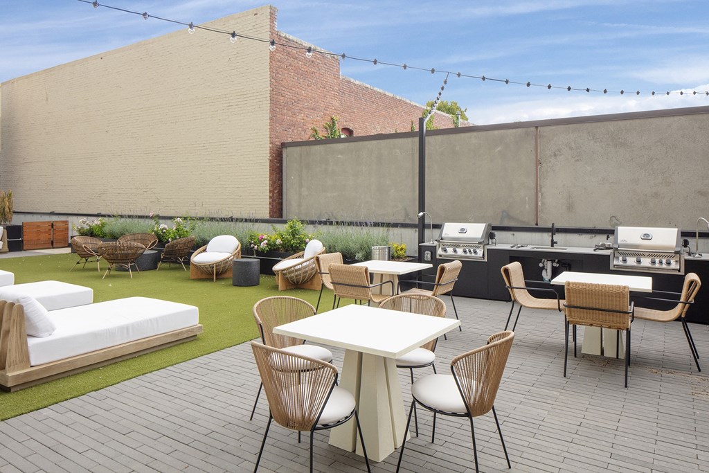 a rooftop patio with tables and chairs and a barbecue grill at The Weidler in Portland, OR 97209