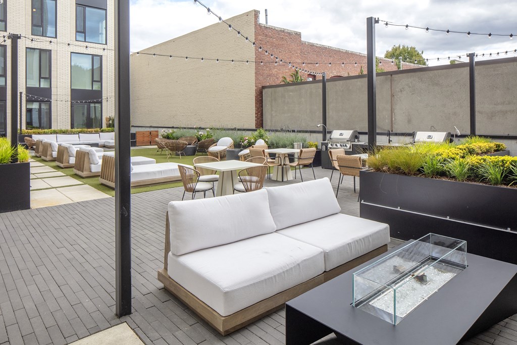 a rooftop patio with a white couch and tables and chairs at The Weidler in Portland, OR 97209