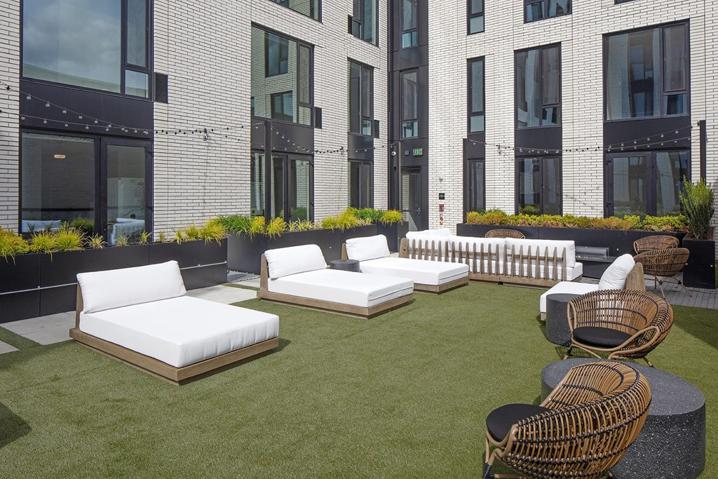 an outdoor lounge area of a building with white couches and chairs at The Weidler in Portland, OR 97209