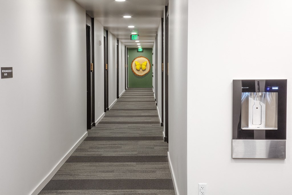 a hallway with a water dispenser and a yellow smiley face on the wall at The Weidler in Portland, OR 97209
