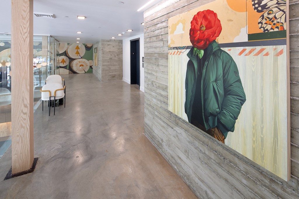 a large painting of a man wearing a red hat on a wall in a hallway at The Weidler in Portland, OR 97209