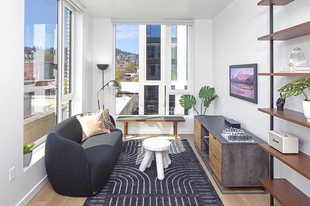 a living room with a black couch and a black and white rug and a window at The Weidler in Portland, OR 97209