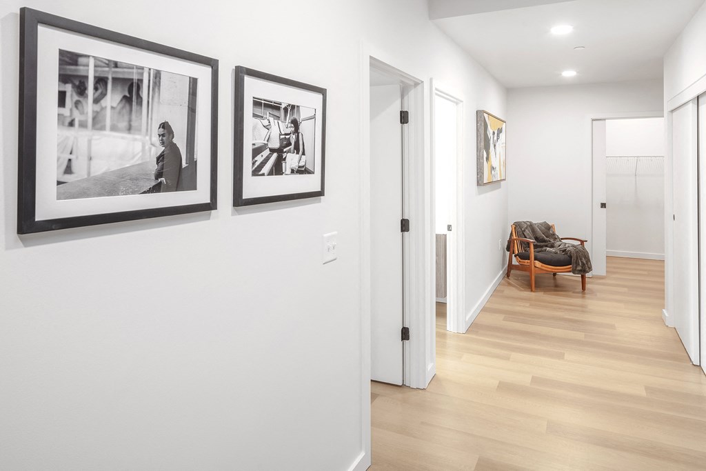 a hallway with pictures on the wall and a door to a living room at The Weidler in Portland, OR 97209