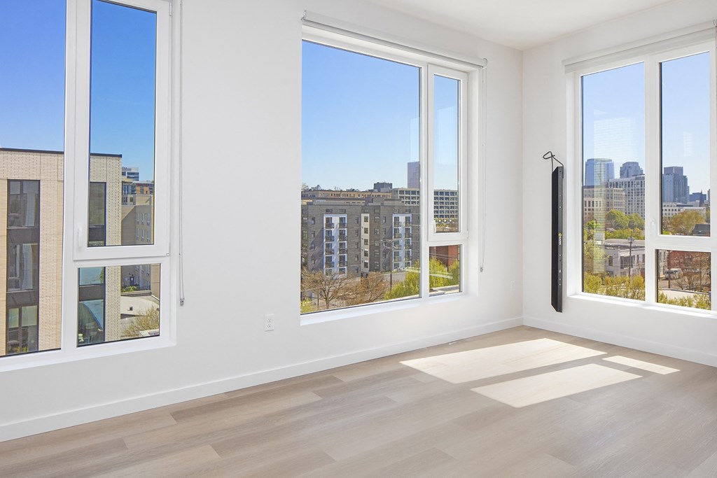 a living room with three windows and a view of the city at The Weidler in Portland, OR 97209