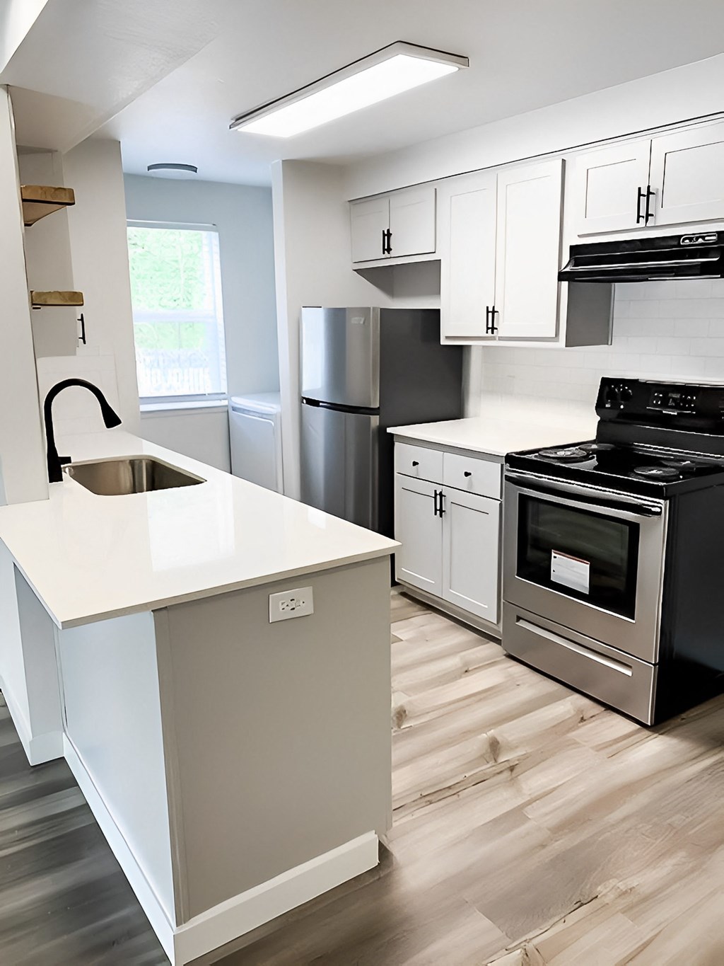 A modern kitchen with a white countertop and stainless steel appliances.