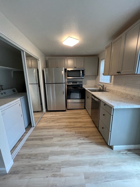 A kitchen with a white refrigerator and wooden floors.