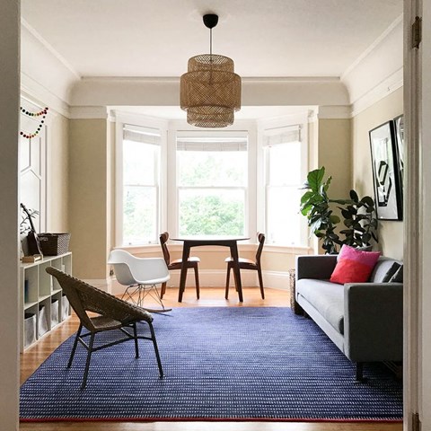 a living room with a blue rug and a table and chairs