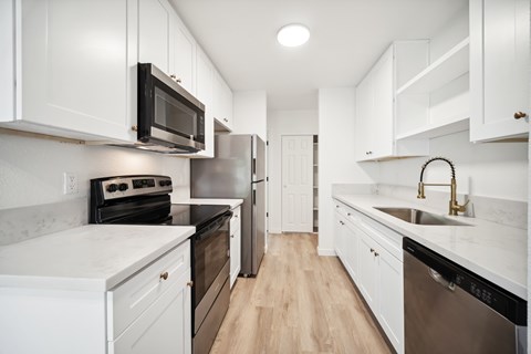 A kitchen with white cabinets and a black microwave.