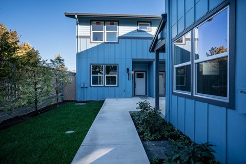 A blue house with a white fence and a green lawn.