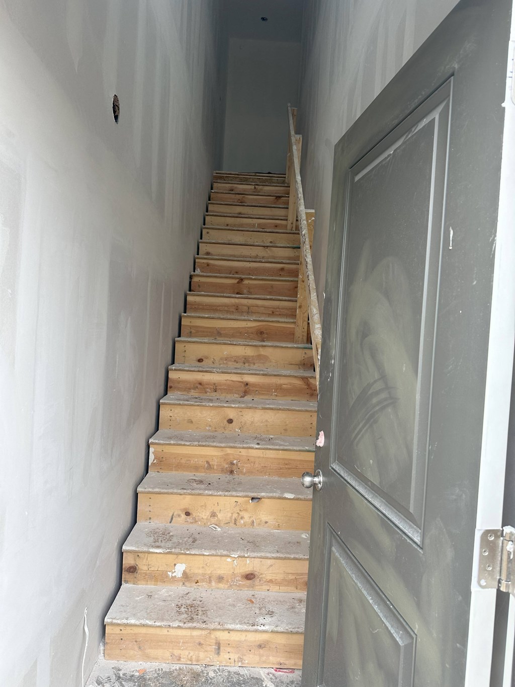 a set of wooden stairs leading up to a gray door