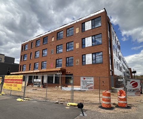 A construction site with a building under construction and a sign for catalyst.
