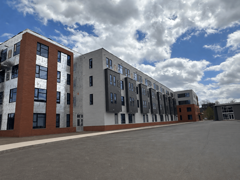 A row of modern buildings with a cloudy sky in the background.