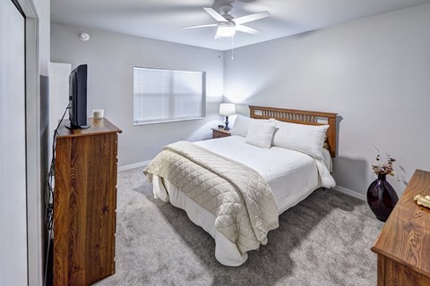 A bedroom with a bed, dresser, and ceiling fan.