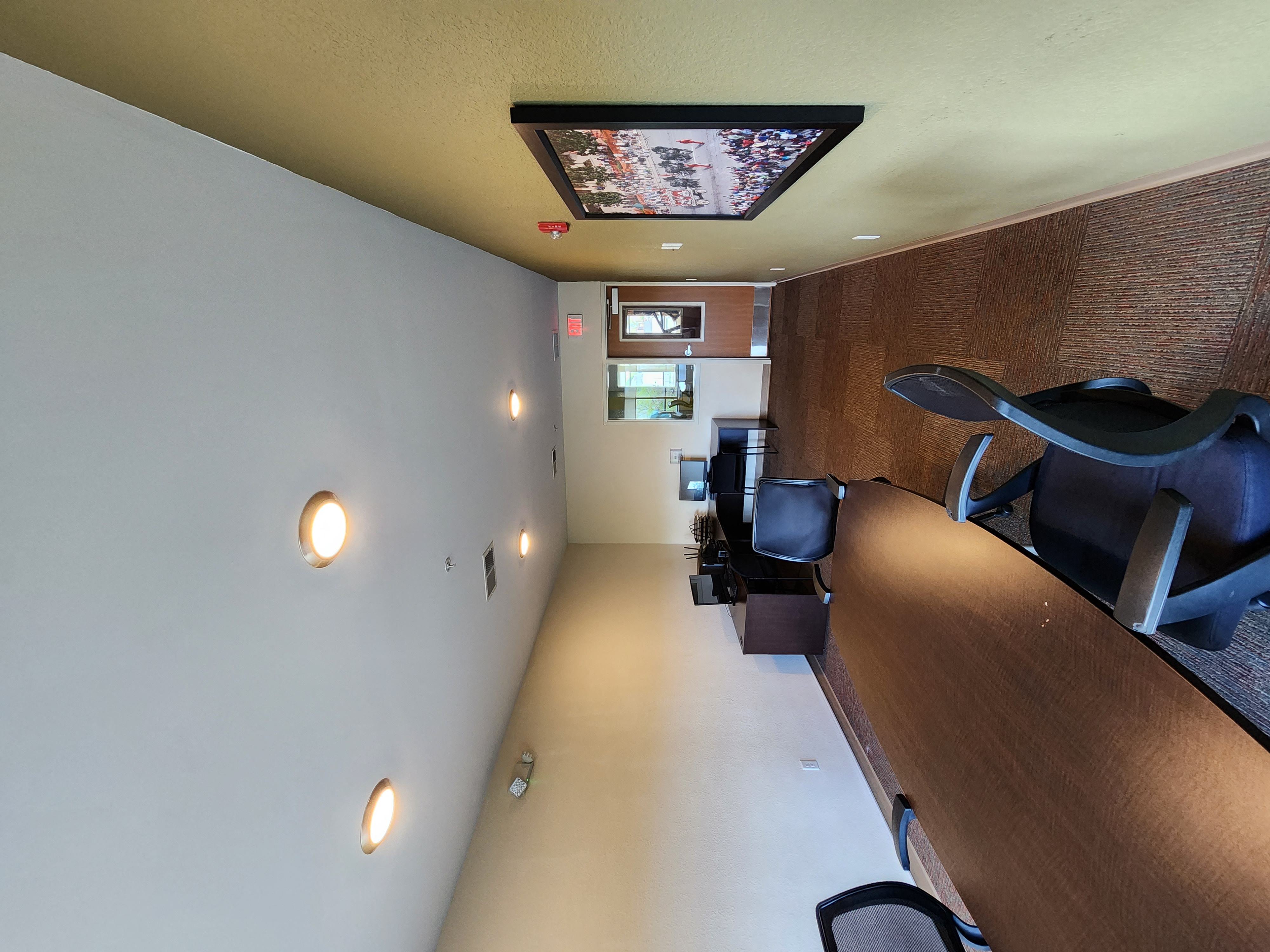 a view of a long hallway with a desk and chairs and a ceiling with lights