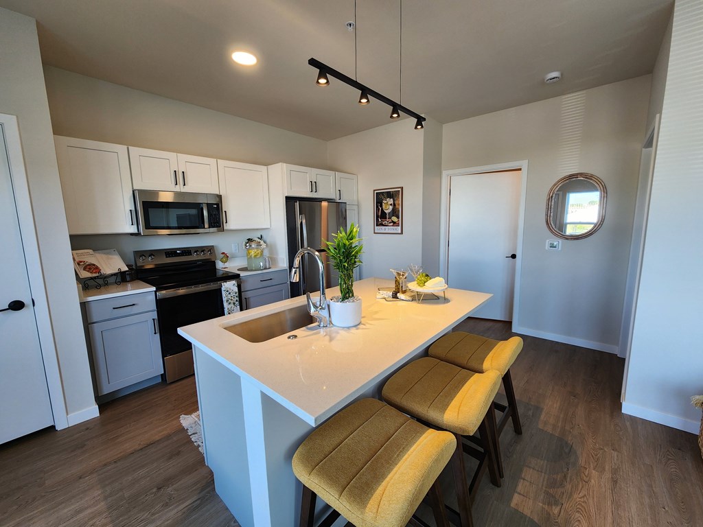 a kitchen with a large island with three stools a kitchen with a large island with three stools at The Daniels at Northern Gateway Apartments, Wisconsin
