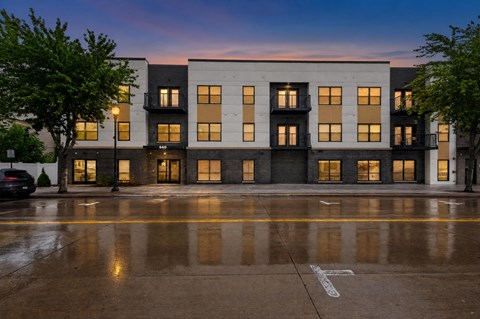 A building with a white facade and multiple windows is illuminated by the setting sun.