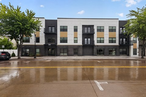 A multi-story building with a black and white facade and a yellow line on the street in front.