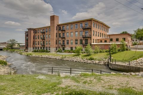 an old factory building sits next to a river