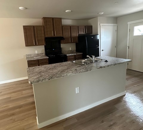 A kitchen with a granite countertop and wooden cabinets.