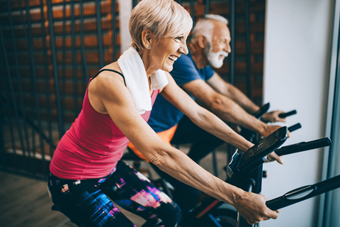 Two people exercising on stationary bikes in a gym.