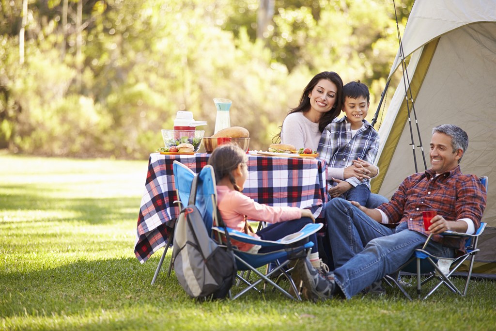 a family sitting at a picnic table outside a tent at The Daniels at Northern Gateway Apartments, Saukville, WI