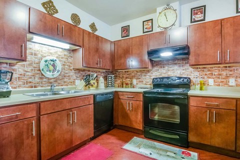 a kitchen with wooden cabinets and black appliances and a clock